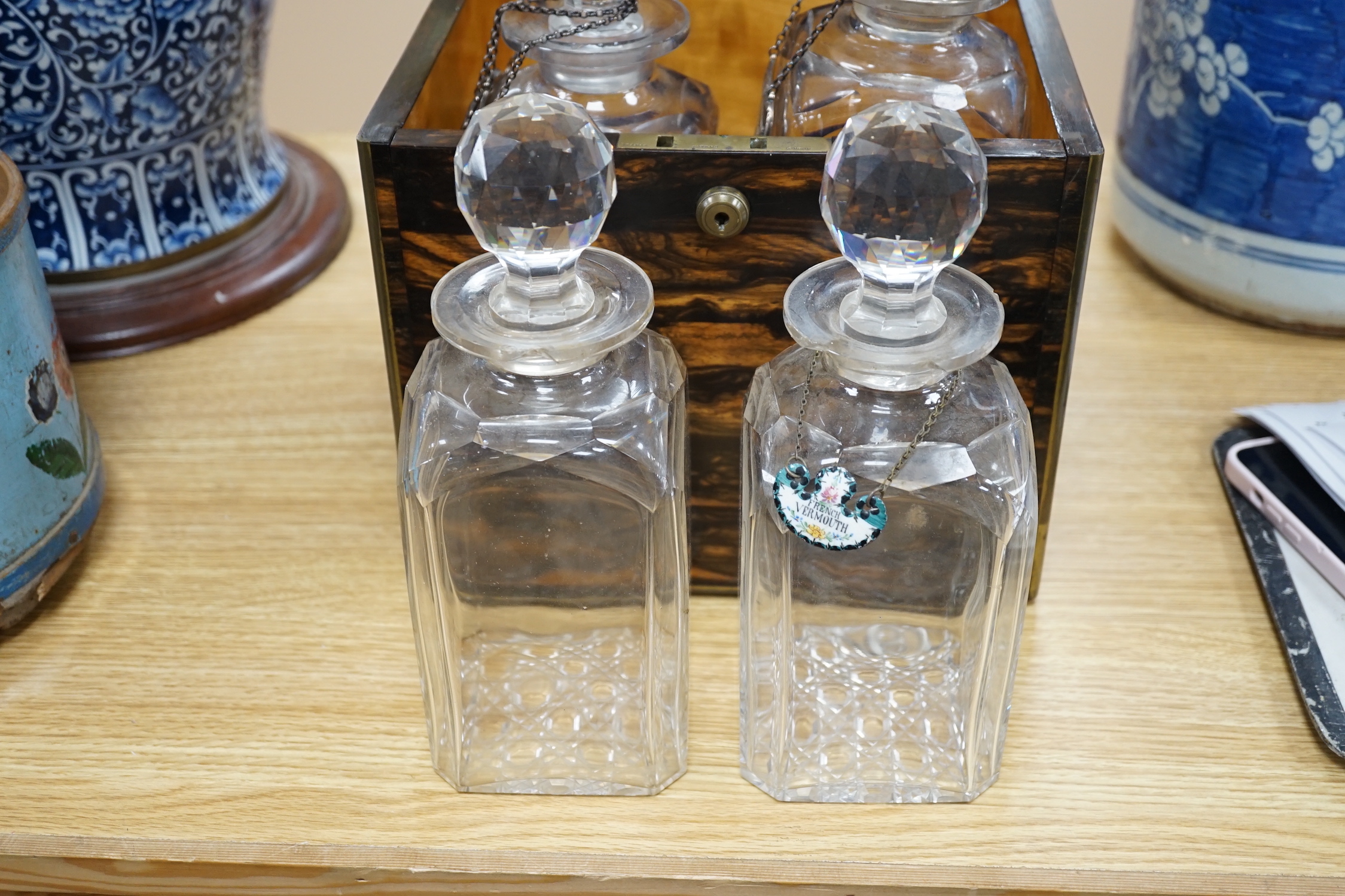 A Victorian coromandel four bottle decanter box with Bramah lock, three silver ‘hunting’ spirit labels and another enamelled, height of box 30cm